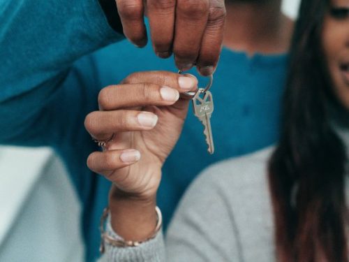 Female holding a key with a key chain in the shape of a house